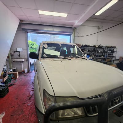 רכב לבן עם זכוכית קדמית בתהליך תיקון