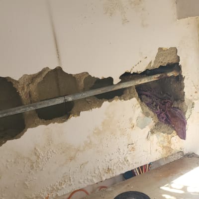 צינור מתכת בקיר שבור עם כלי עבודה על שולחן