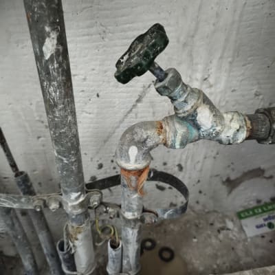 צינורות וברז ישן עם חלודה על קיר בטון