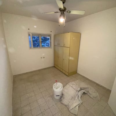 דלי צבע ומברשת על רצפה בחדר ריק