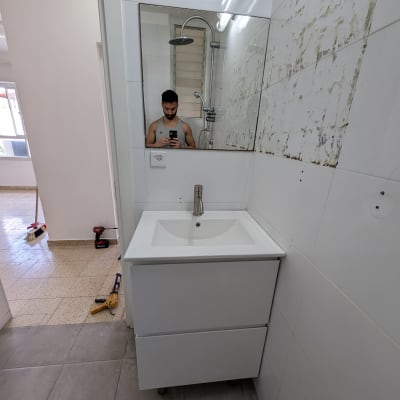 כיור עם ברז, מקדחה ומברג על הרצפה