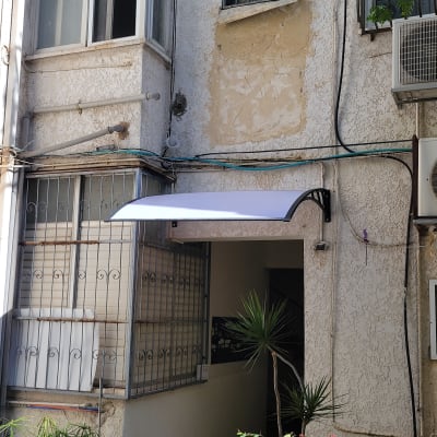 סוכך מותקן מעל כניסה לבניין עם קירות טיח.