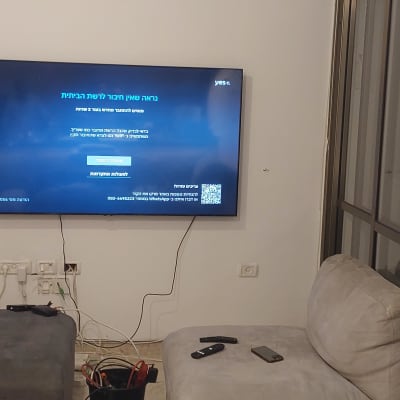 טלוויזיה תלויה על הקיר עם כבלים חשמליים וציוד תיקון