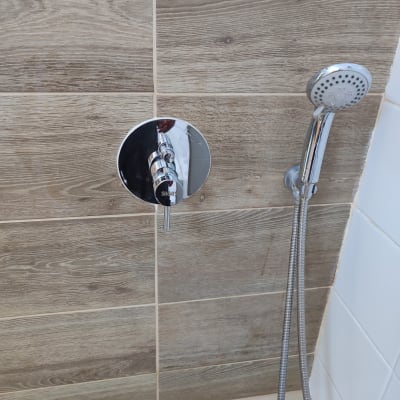 ברז מקלחת עם ידית וכפתור על קיר אריחים