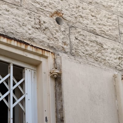 חור בקיר ליד חלון עם סורג מתכת