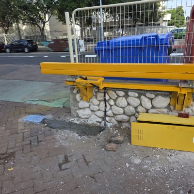 שער חשמלי צהוב מותקן על קיר אבן