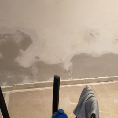 קיר עם תיקוני צבע וכיסא עם בקבוק