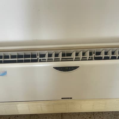 מזגן קיר לבן עם תריסים פתוחים ותצוגת טמפרטורה