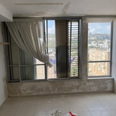 חדר בשיפוץ עם קירות מטויחים ורצפה מלוכלכת