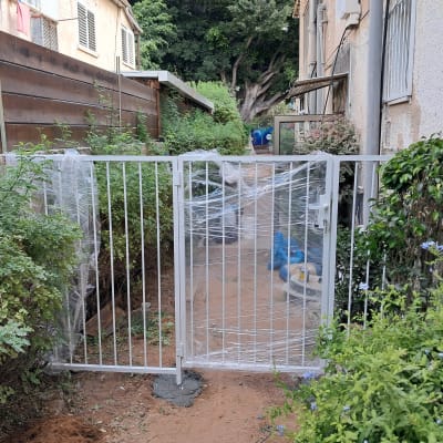 שער מתכת לבן עטוף בניילון בגינה