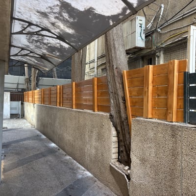 גדר עץ חדשה לצד שביל בטון