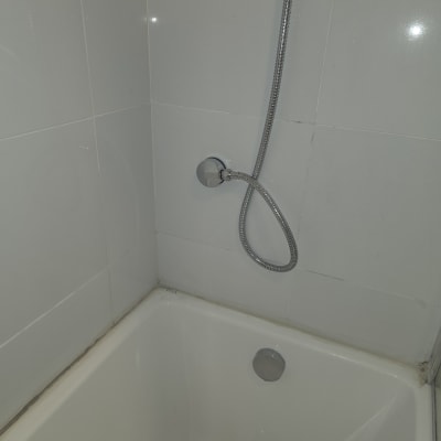 אמבטיה עם צינור מקלחת על קיר אריחים לבנים