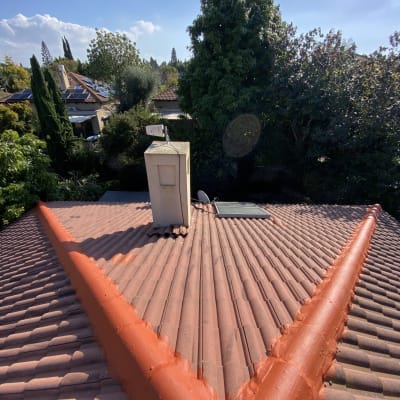 גג רעפים עם צינור אדום ומתקן על הארובה