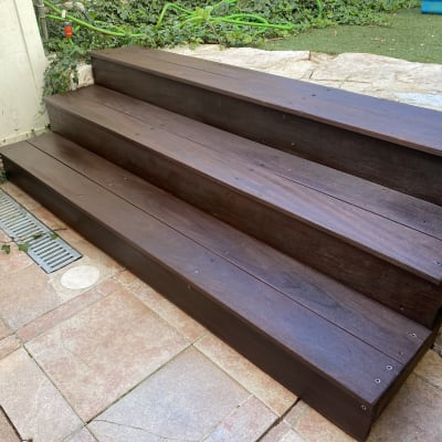 מדרגות עץ כהות בגינה עם צמחייה מסביב