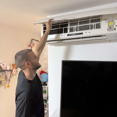 אדם פותח מכסה של מזגן קיר