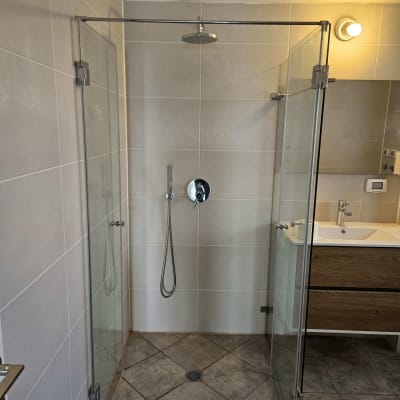 מקלחון זכוכית עם ראש מקלחת ותאורה בחדר אמבטיה מודרני