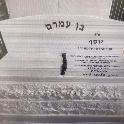 מצבה עם כיתוב בעברית ואבנים קטנות מונחות עליה