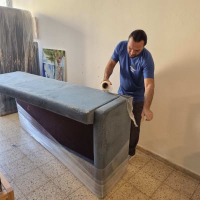 אדם עוטף רהיט בניילון לקראת מעבר דירה