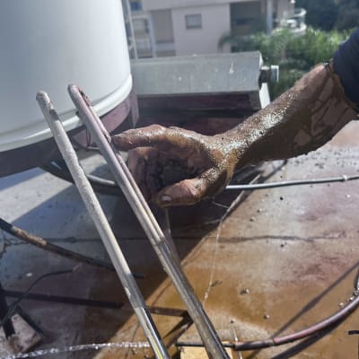 יד מלוכלכת מחזיקה צינור ליד דוד שמש