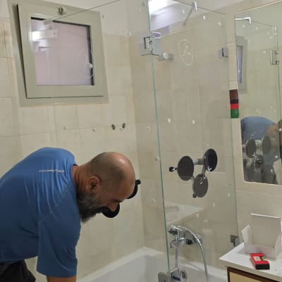 אדם מתקין דלת זכוכית במקלחת עם אמבטיה