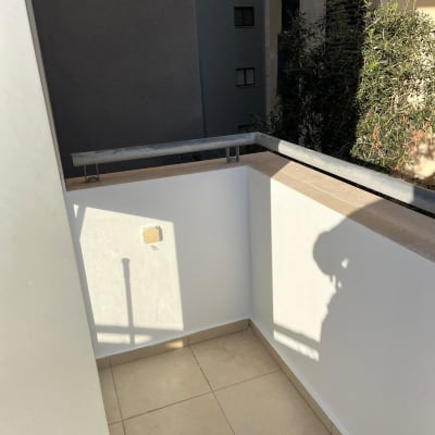 מרפסת קטנה עם קירות לבנים ומעקה מתכת