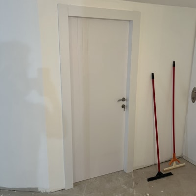 דלת לבנה עם ידית כסופה על קיר לבן