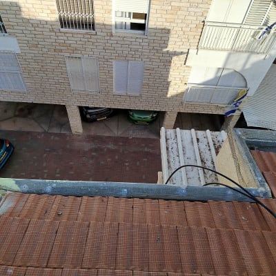 תמונה של גג עם רשתות ומבנה סמוך