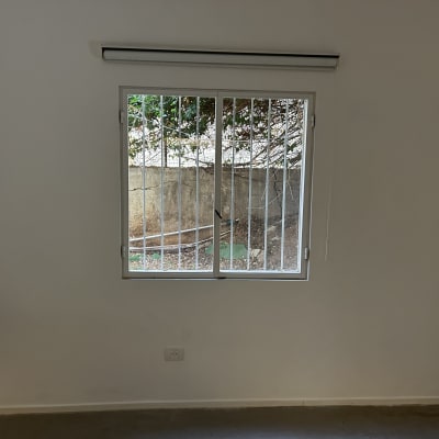 חלון עם סורגים על קיר לבן בחדר ריק