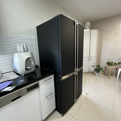 מטבח עם מקרר שחור ומכשירי חשמל נוספים