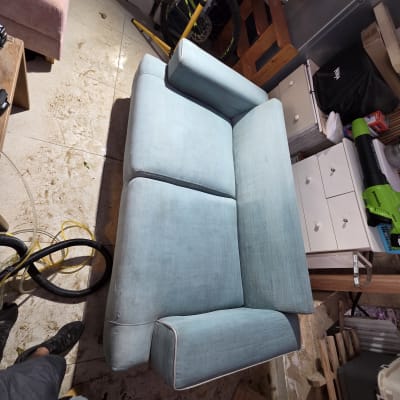 ספה כחולה בתהליך ניקוי עם ציוד ניקוי