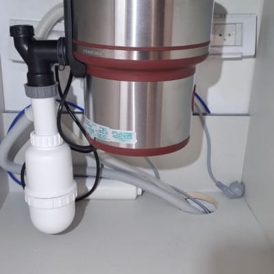 מתקן טוחן אשפה מתחת לכיור עם צינורות וחיבורים