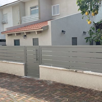 גדר מתכת אפורה עם שער, ליד בית מודרני