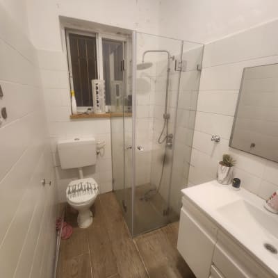 מקלחת עם דלת זכוכית ושירותים בחדר אמבטיה