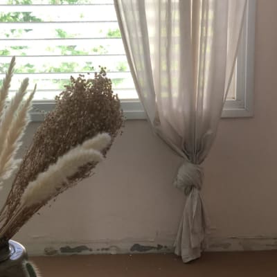 קיר עם סימני צבע מתקלף ליד חלון עם וילון