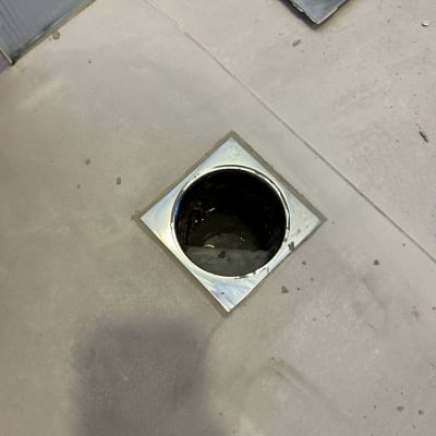 פתח ניקוז מרובע ברצפה עם מכסה פתוח