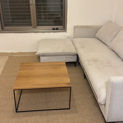 ספת בד בהירה עם כתמי לכלוך בסלון לצד שולחן ושטיח