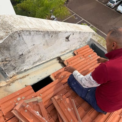 אדם עובד על גג עם רעפים אדומים