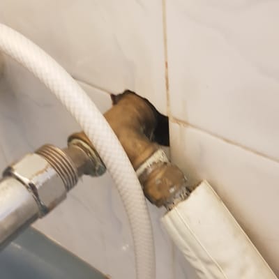 צינור מים מחובר לברז בקיר עם חור