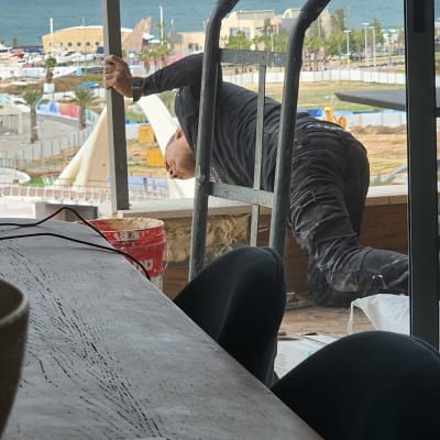 עובד מבצע עבודת שיפוץ במרפסת עם נוף לים