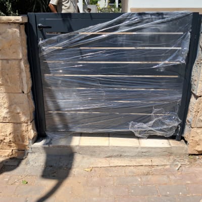 שער מתכת עטוף בניילון בין קירות אבן