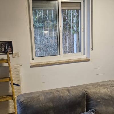 חלון עם תריסים וספה בחדר מגורים