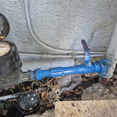 ברז מים כחול וצינור ליד קיר בטון