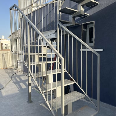 מדרגות מתכת עם מעקה על רקע קיר כחול