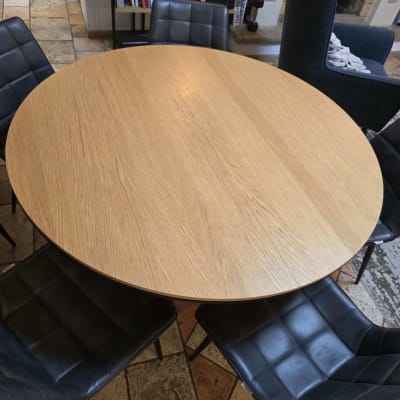 שולחן אוכל עגול מעץ וכיסאות מרופדים בפינת אוכל