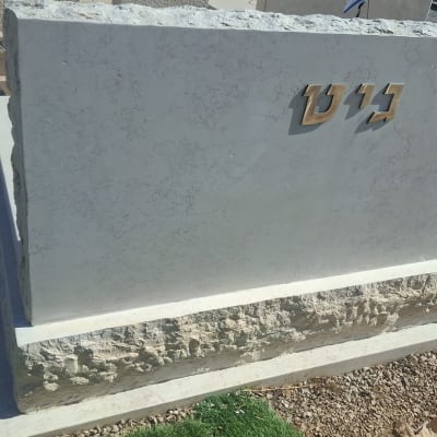 מצבה עם כיתוב בעברית על רקע חצץ