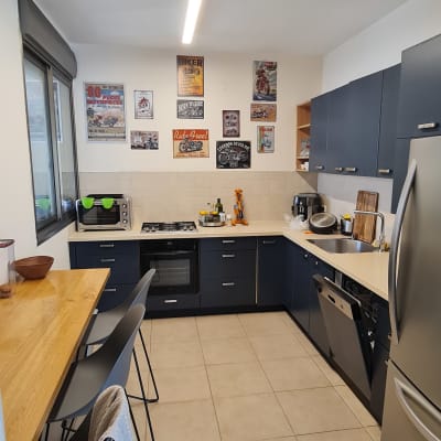 מטבח מודרני עם ארונות כהים ומכשירי חשמל.