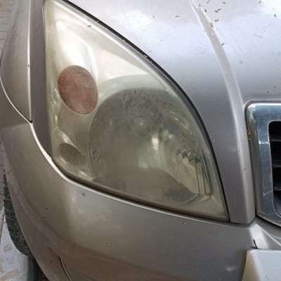 פנס קדמי מלוכלך של רכב עם גריל מתכתי