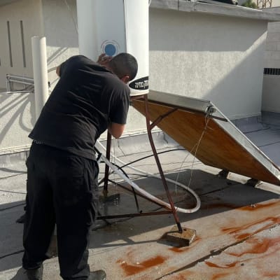 אדם מתקן דוד שמש על גג עם קולטים