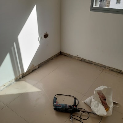 חדר עם קיר לבן, מקדחה ושק על הרצפה