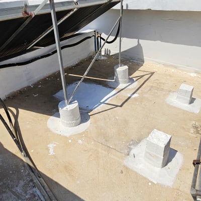 גג עם עמודי מתכת ואיטום לבן סביבם